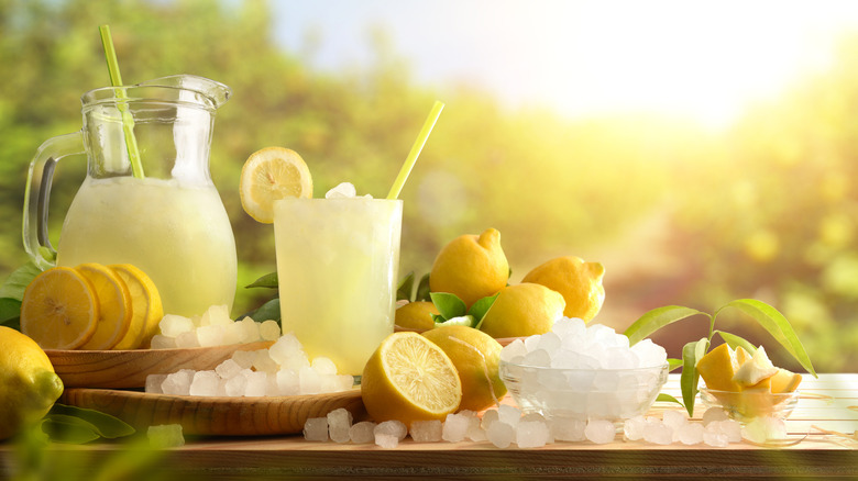Iced lemonade and ingredients on a table at sunset.