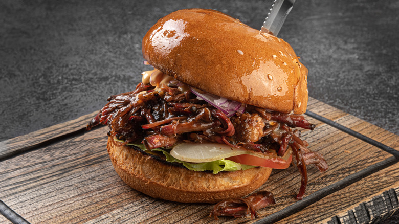 a pulled pork sandwich on a wooden cutting board