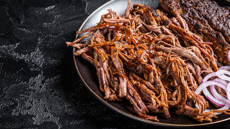 a plate of sauced pulled pork with red onions