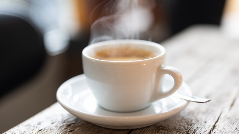 Cup of hot coffee on a white plate 