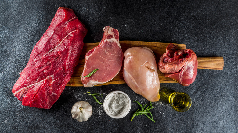 Different types of beef, pork, and chicken on a wooden board