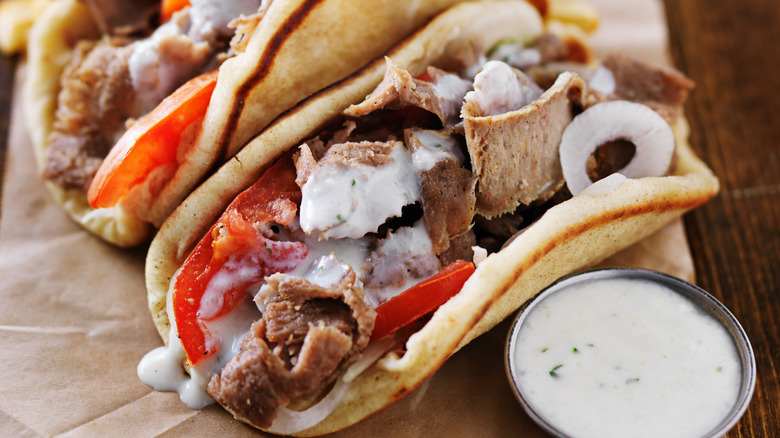 Gyros with thin meat on a paper napkin with tzatziki sauce
