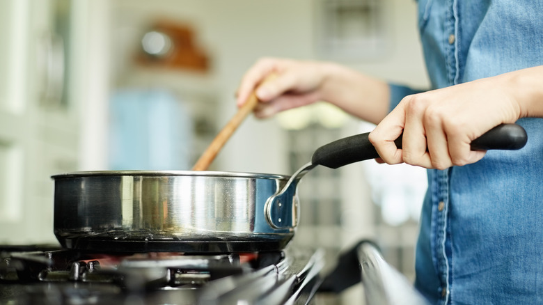 Person stirring pot on stove