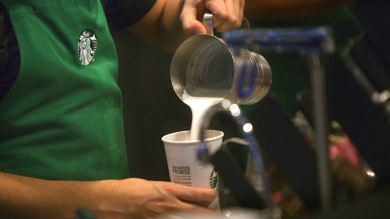 starbucks barista pouring hot milk