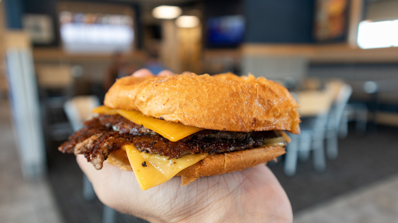 Close-up of a hand holding a Culver's ButterBurger with cheese