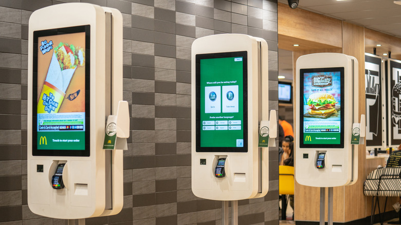 A row of three self-serve menus inside a McDonald's