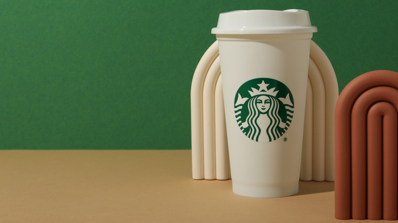 A Starbucks venti cup sits with a green background