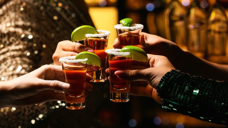 hands holding shots of tequila with salt