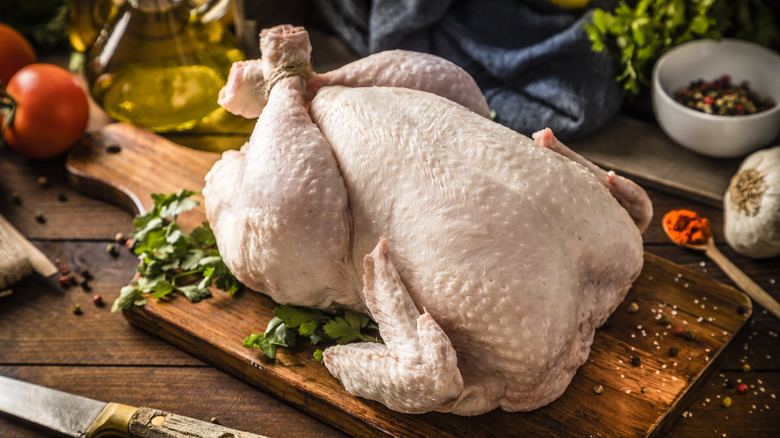 whole chicken on a cutting board with herbs