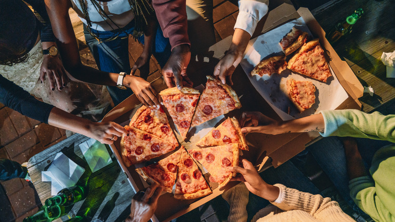 People grabbing pizza slices