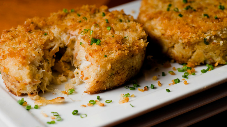 Crab cakes garnished chives on a white plate