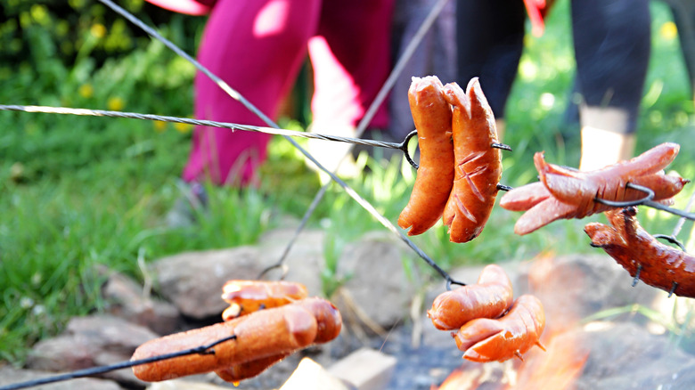 Hot dogs split apart while being roasted on a campfire