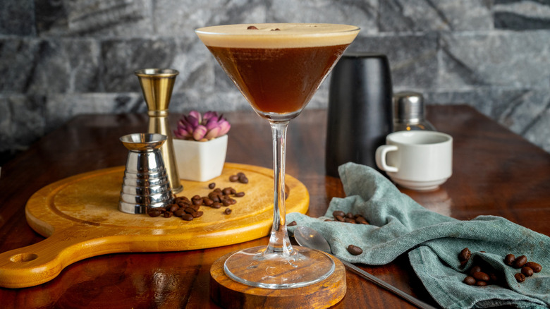 Espresso martini pictured alongside bartending tools.