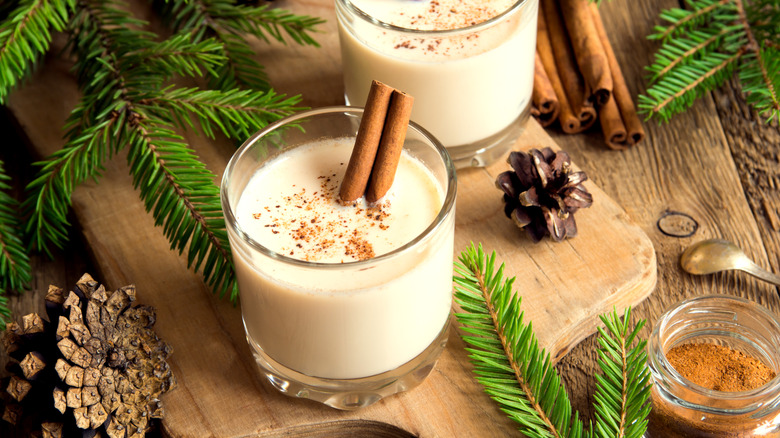 A glass of eggnog with cinnamon sticks.