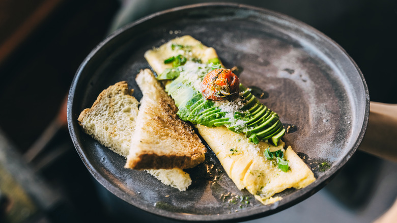 Omelet on a black plate with toast.