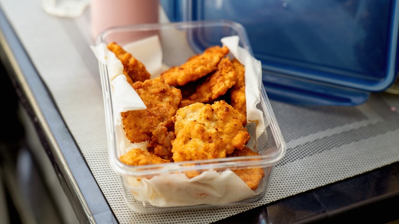 Breaded chicken breasts in open storage container.