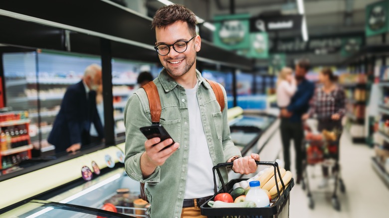 person checking their phone while shopping at a supermarket