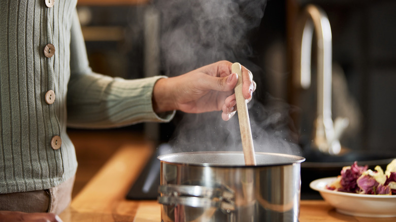 Person cooking food on a stovetop in a kitchen.