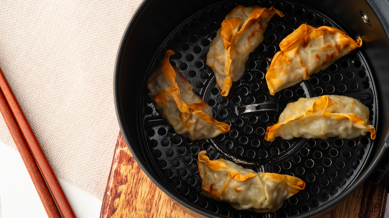 Gyoza in an airfryer basket next to chopsticks
