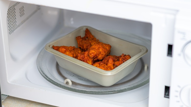 Piece of fried chicken heating in the microwave