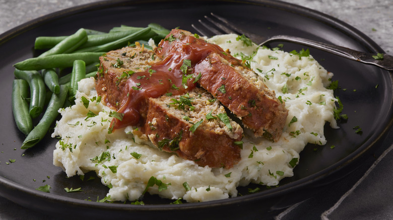 Two slices of meatloaf on rice with green beans