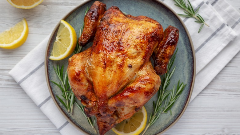 Rotisserie chicken on a plate with lemon and herbs