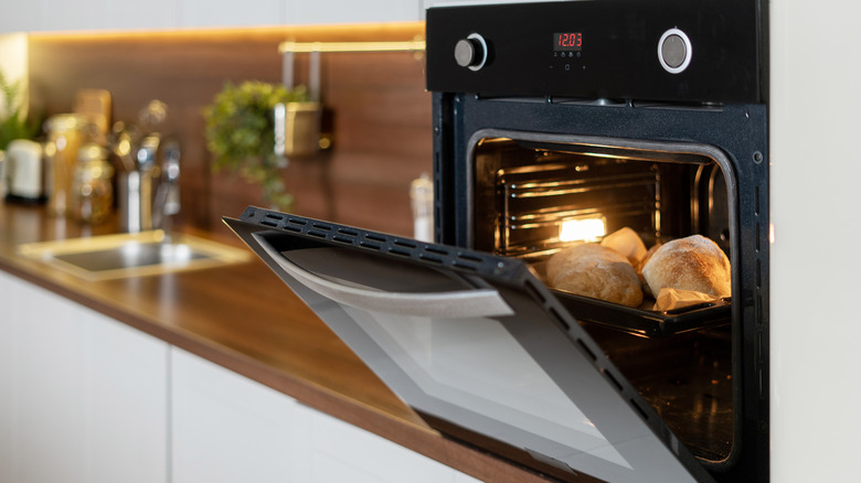 Open oven door with bread loaves inside