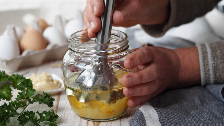 Person blending mayonnaise ingredients in a jar