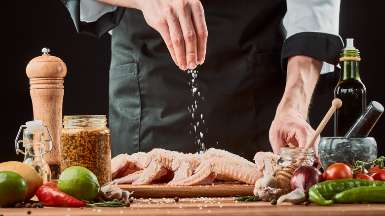 adding seasoning to wings