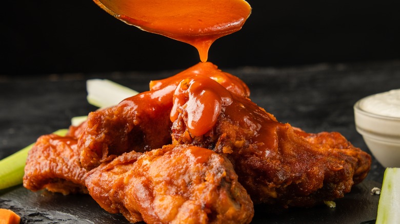 adding buffalo sauce to wings