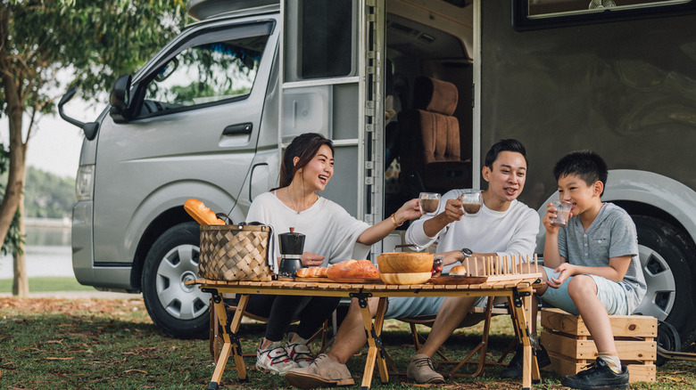 Asian family with camper van at public park