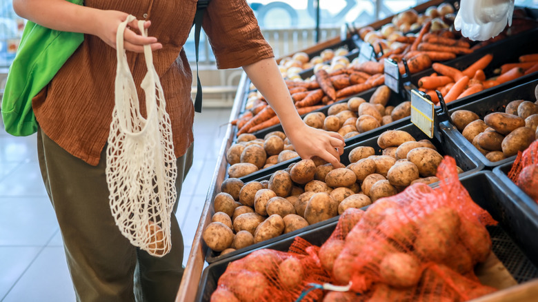 A shopper selects some potatoes in the grocery store