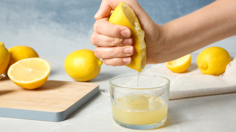 squeezing lemon juice into glass