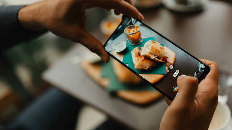 A diner taking pictures of a meal on a phone.