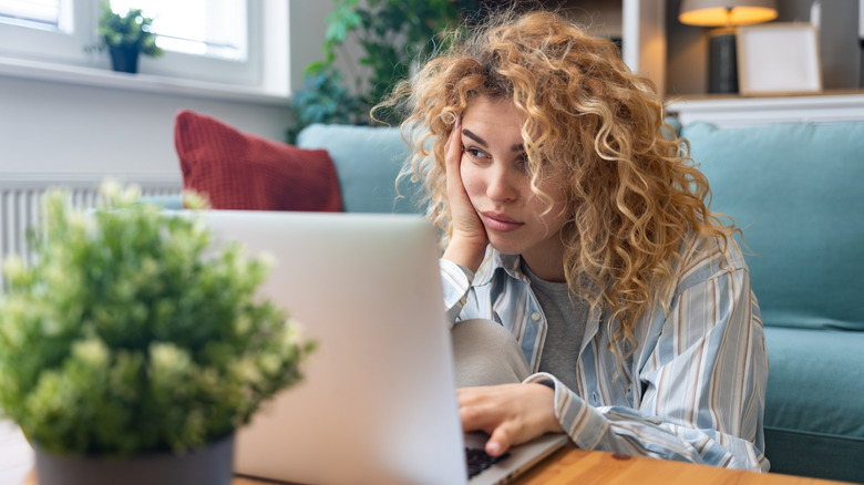 A person at home struggling to understand something on a laptop.
