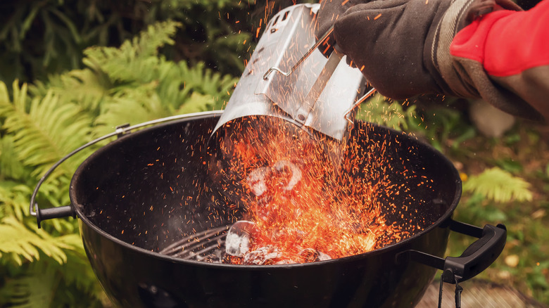 man with glove using chimney starter for grill