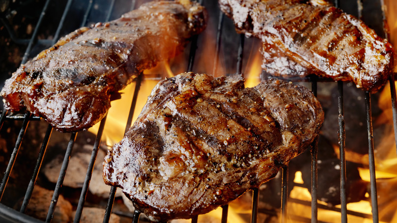 steaks cooking on charcoal grill