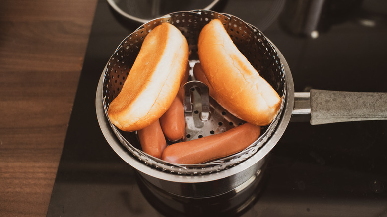 Hot dog buns and hot dogs in a steamer basket