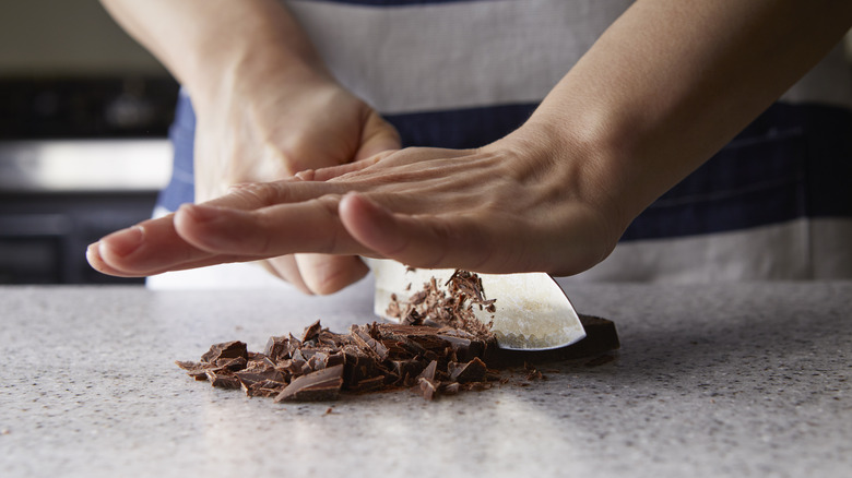 Person chopping up chocolate in kitchen