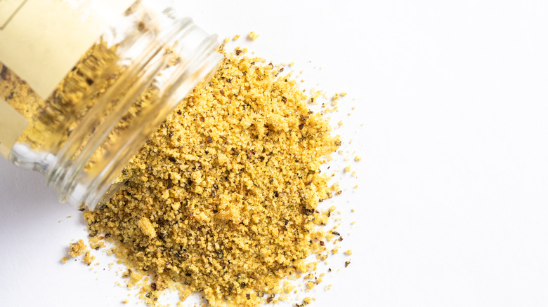 A jar of lemon pepper spilling out on a counter