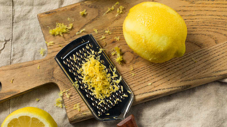 A lemon sits next to a grater full of zest