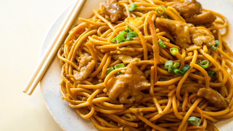 A plate of lo mein with chopsticks