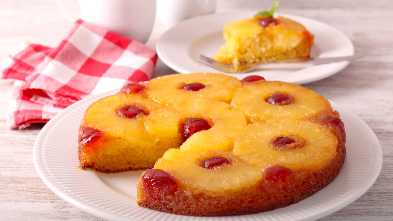 Pineapple upside down cake on a round plate, with a slice cut from it sitting on an adjacent plate