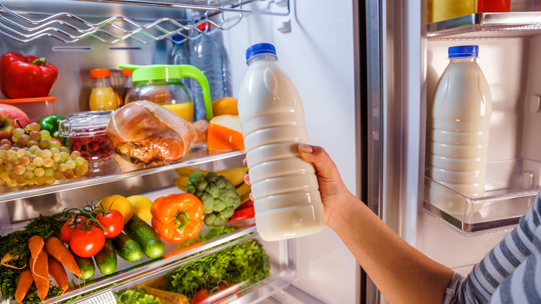 Person putting milk in a fridge