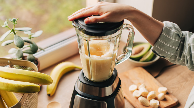 Someone blends a banana smoothie.