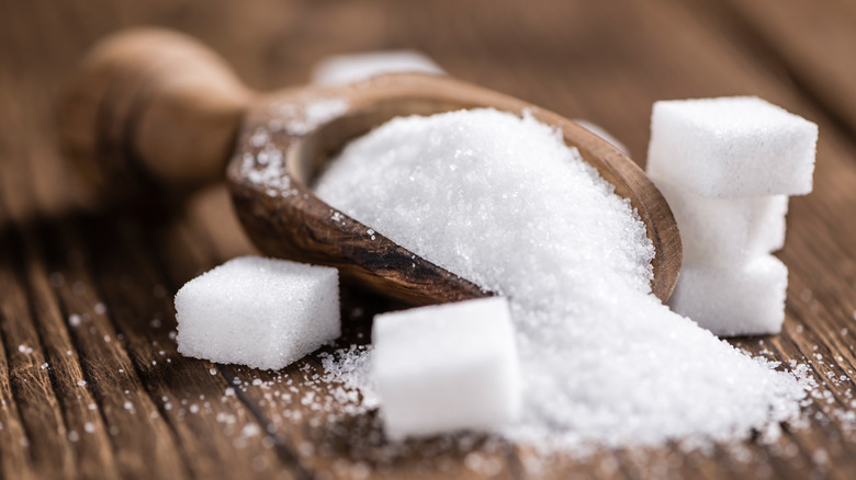 White granulated sugar with cubes and wooden spoon