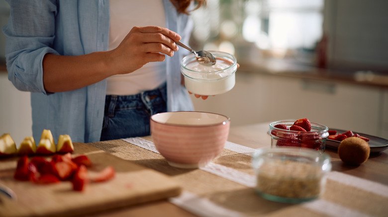 A woman scooping yogurt into a bowl
