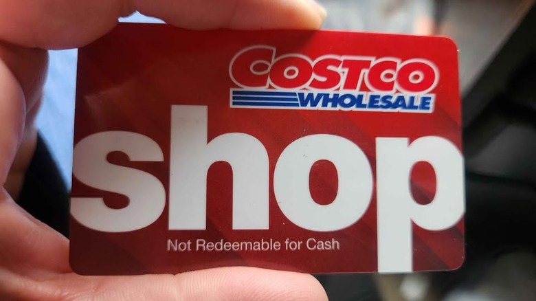 A hand holds up a Costco Shop Card