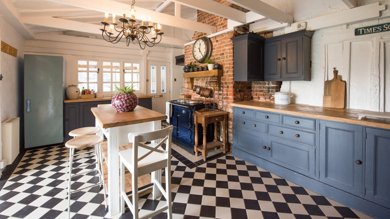 A charming kitchen with black-and-white checkered floor and blue cabinets is illuminated by sunlight