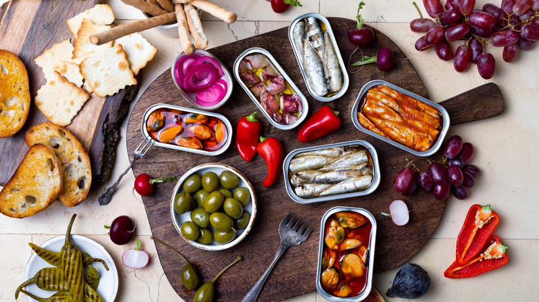 charcuterie board with tinned fish, fruit, and crackers